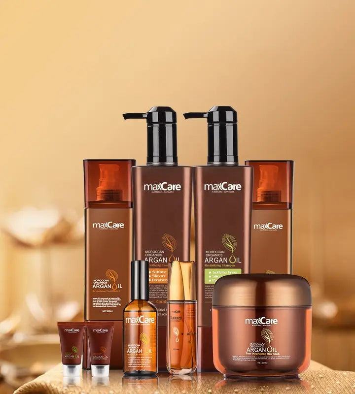 MaxCare Moroccan Argan Oil hair care collection displayed on a warm golden background. The set includes revitalizing shampoos, conditioners, hair oils, hair masks, and small travel-size products, all in elegant amber and brown packaging.